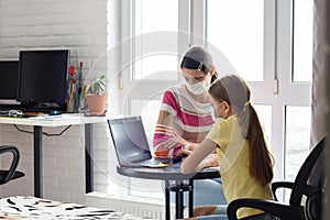 Mom helps daughter do homework, both in medical protective masks