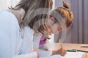 mom helps daughter do homework at home in elementary school