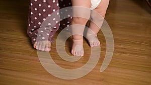 Mom helps her little son learn the first steps. The child learns to walk