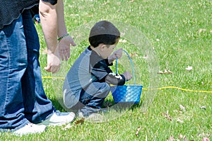 Mom helps Little boy in a Easter egg hunt