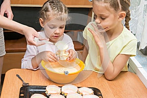 Mom helps subsidiaries pour batter into molds for baking cakes