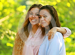 Mom and her adult daughter are hugging in the park, summer day