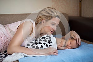 Mom and her baby are lying on the bed with a blue blanket