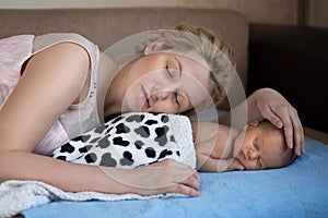 Mom and her baby are lying on the bed with a blue blanket