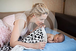 Mom and her baby are lying on the bed with a blue blanket