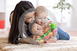 Mom and her baby son play with toy in cosy children room