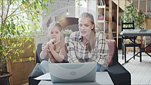 Mom and her child study together with a music tutor through a laptop