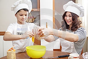 Mom and her child in white chef hats preparing an omelet in the kitchen.