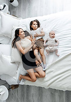 Mom and her children are lying on the bed in a bright bedroom, top view