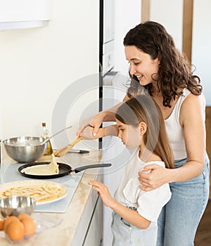 Mom and her daughter fry pancakes