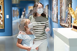 Mom and her daughter in protective masks on tour of the museum