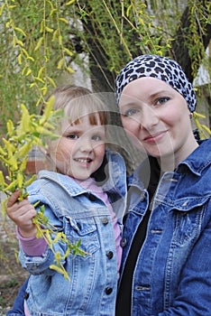 Mom with her daughter standing near willow