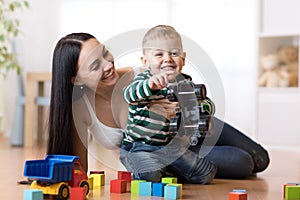 Mom and her kid son plays with car in nursery room