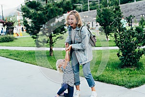 Mom and her little daughter have fun in the park, play and laugh.