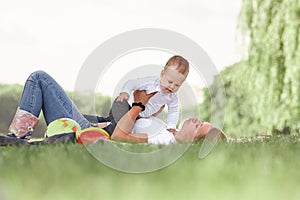 Mom and her little son play together, lying on the lawn .