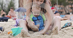 Mom and her son are building sand castles on the beach.