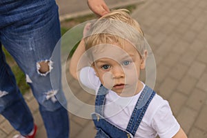 Mom and her son walk in the park in identical denim jumpsuits. they enjoy time together and love each other