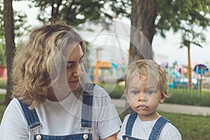 Mom and her son walk in the park in identical denim jumpsuits. they enjoy time together and love each other