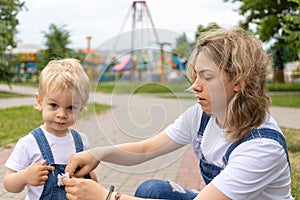 Mom and her son walk in the park in identical denim jumpsuits. they enjoy time together and love each other