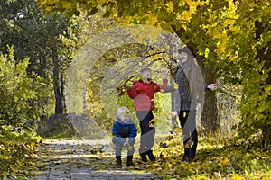Mom and her sons toss the leaves. Autumn Park.