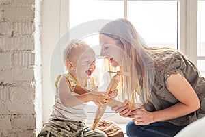 Mom and her toddler son plays with wooden plane toy