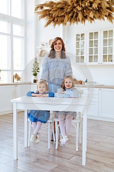 Mom with her two children sitting on the kitchen table.