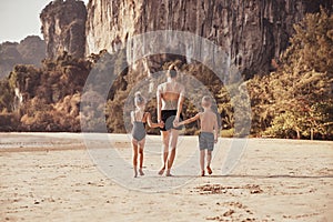 Mom and her two children walking down along sandy beach