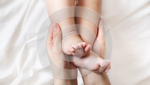 Mom is holding the baby`s tiny feet. Small baby feet on female hands close up. Happy family concept.Beautiful conceptual image of