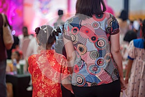 mom holding hand of girl with red China satin qipao cheongsam