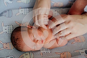 Mom holding hands of newborn. children sleeps. cosmetics for skin care