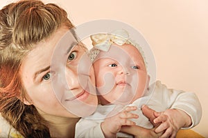 Mom holds the baby in her arms and poses for the camera in the studio, the concept of love and unity and care for loved ones and