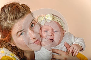 Mom holds the baby in her arms and poses for the camera in the studio, the concept of love and unity and care for loved ones and