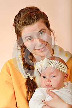 Mom holds the baby in her arms and poses for the camera in the studio, the concept of love and unity and care for loved ones and