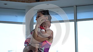 Mom holds the child and rocks his back, bending and unbending standing in the gym for yoga