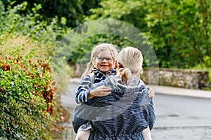 Mom holds her little daughter on hands standing under umbrella. Mother and happy preschool girl, child with eyeglasses
