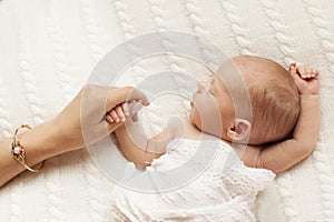 Mom holds her newborn daughter by the hand