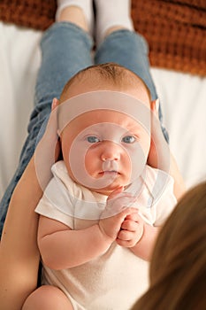 mom holds a newborn baby in her arms. in the background the sun shines from the window