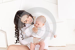 Mom holds newborn baby in her arms at home, happy loving family concept, mother`s day