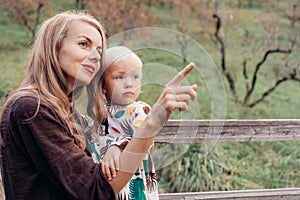 Mom holds Toddler`s daughter in her arms and shows her something with her finger