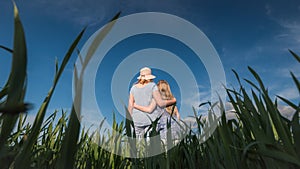 Mom hugs daughter, stand on a beautiful green meadow against a clear blue sky