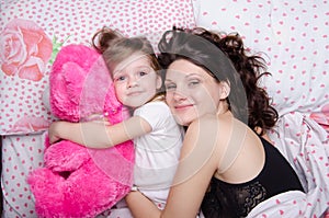 Mom hugs her daughter lying in bed