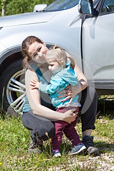 Mom hugs and soothes her daughter near the car