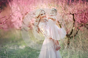 Mom with an infant in the rose garden with flowers trees