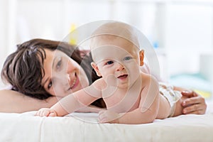 Mom and infant son lying down on bed and mother embracing the infant baby