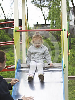 Mom insures her daughter when she comes down from the children slide