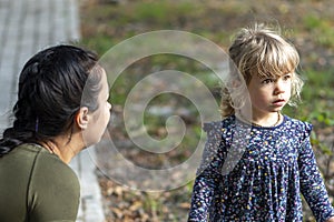 Mom interacts with her daughter on a walk in the park in the fall.