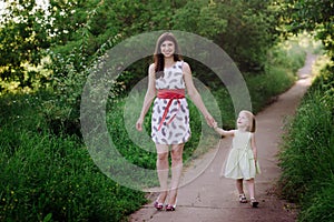 Mom keeps daughter's hand and walks the walk on the nature in sunset light