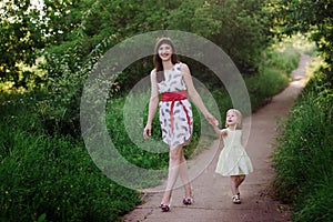 Mom keeps daughter's hand and walks the walk on the nature in sunset light