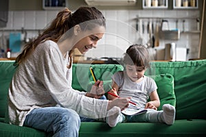 Mom and kid girl drawing with colored pencils at home