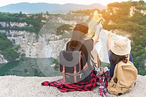 Mom and kid holding maps and travel backpacks sitting victorious facing on the grand canyon for education nature.